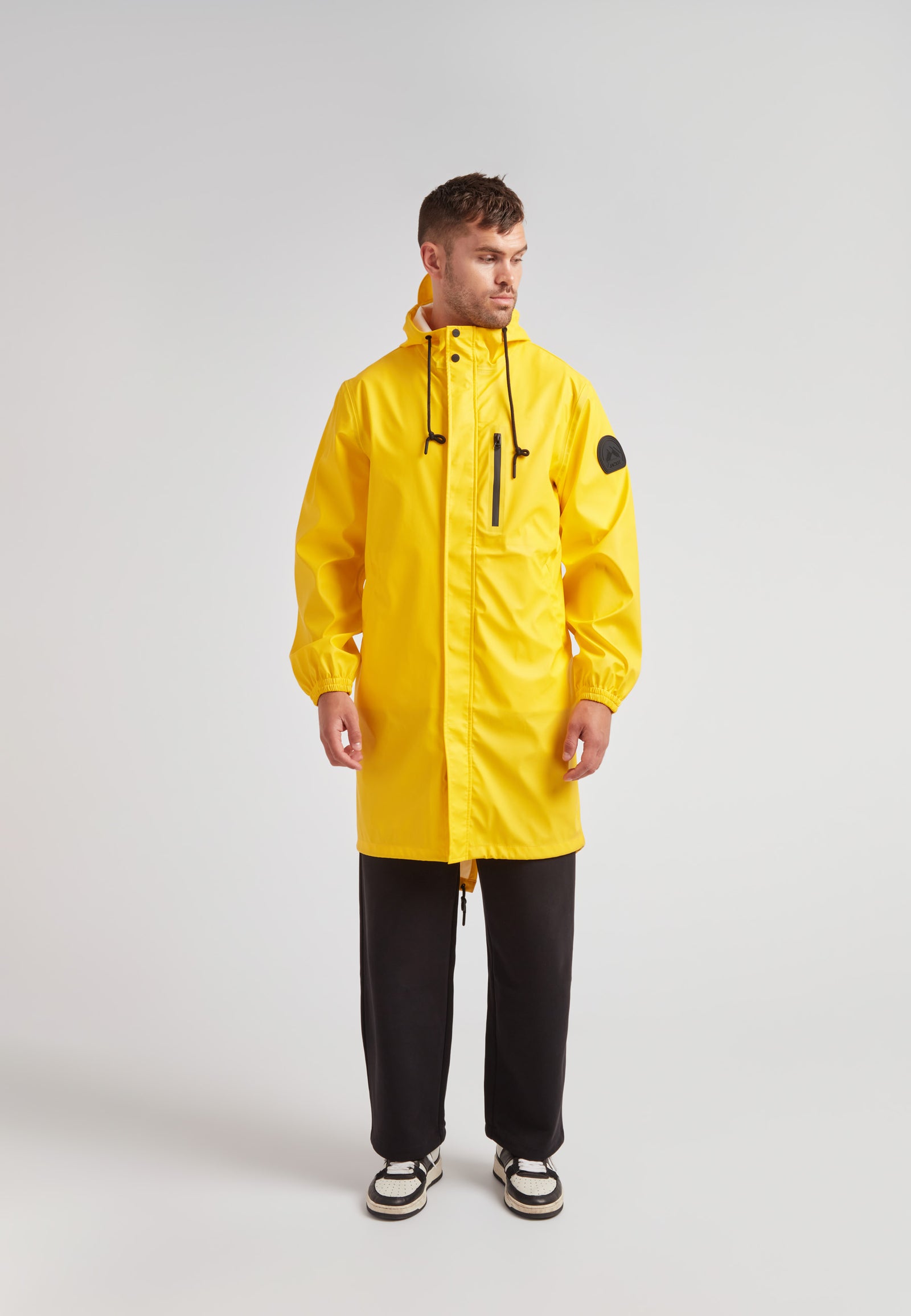 Model showcasing a yellow unisex long raincoat from ELEMENTS collection, designed for lightweight comfort and style.
