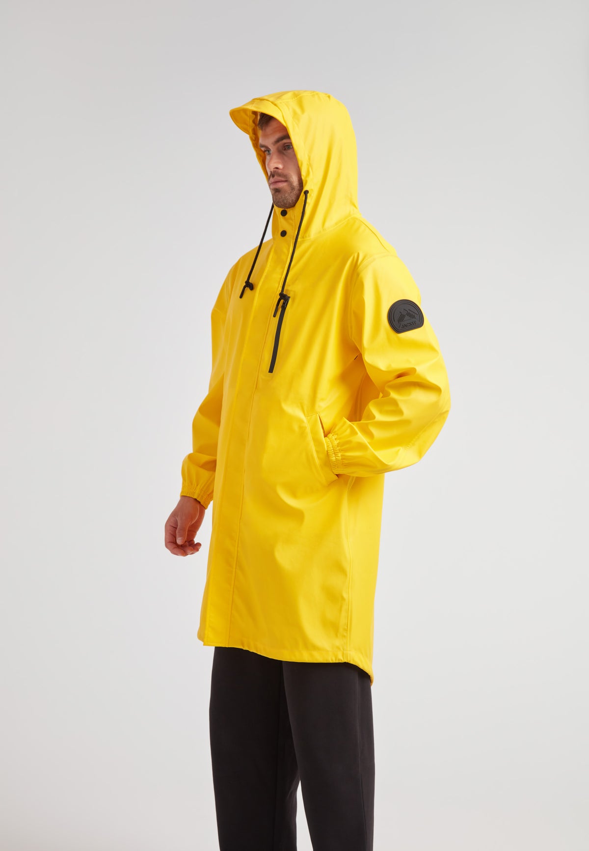 Yellow unisex long raincoat worn by a model, showcasing the lightweight design and hood.