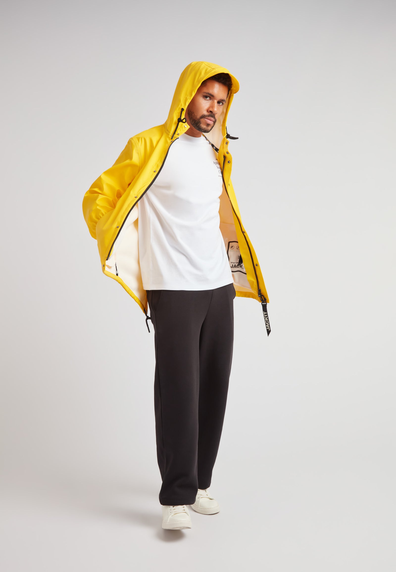 ELEMENTS Unisex Raincoat 2.0 Yellow worn by a man with a white shirt and dark pants, showcasing its vibrant design.