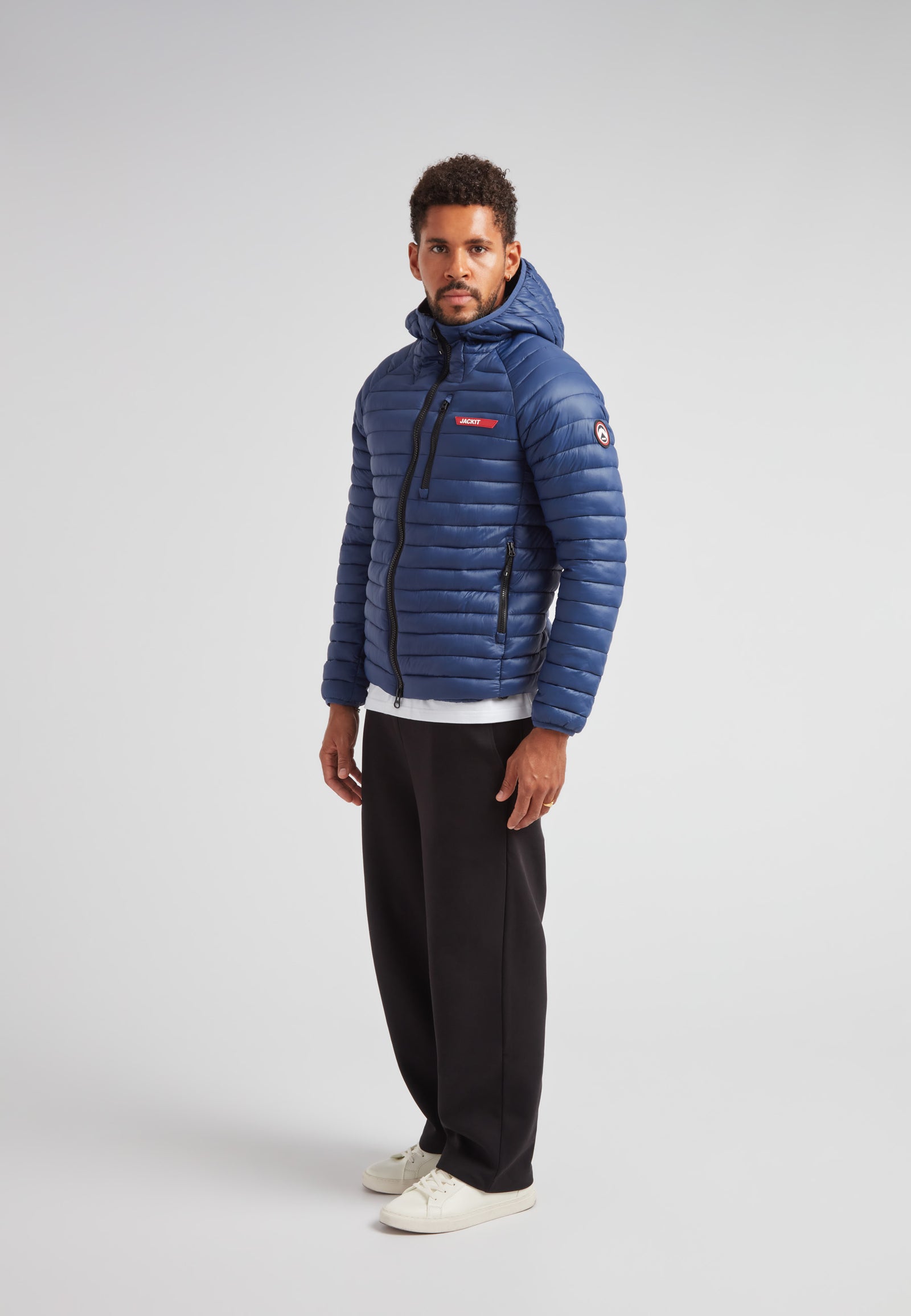 Man wearing SATEL1TE hooded jacket 2.0 pacific blue, showcasing its sleek design and performance features.