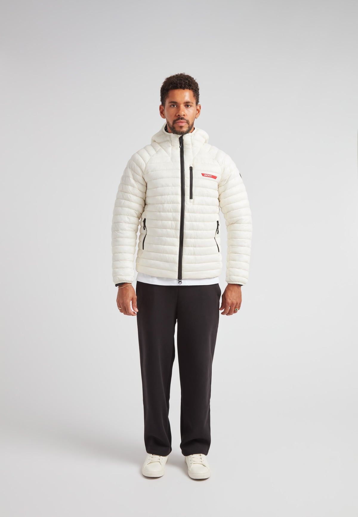 A model wearing the SATEL1TE Hooded Jacket 2.0, a white insulated jacket with a hood and stylish design.