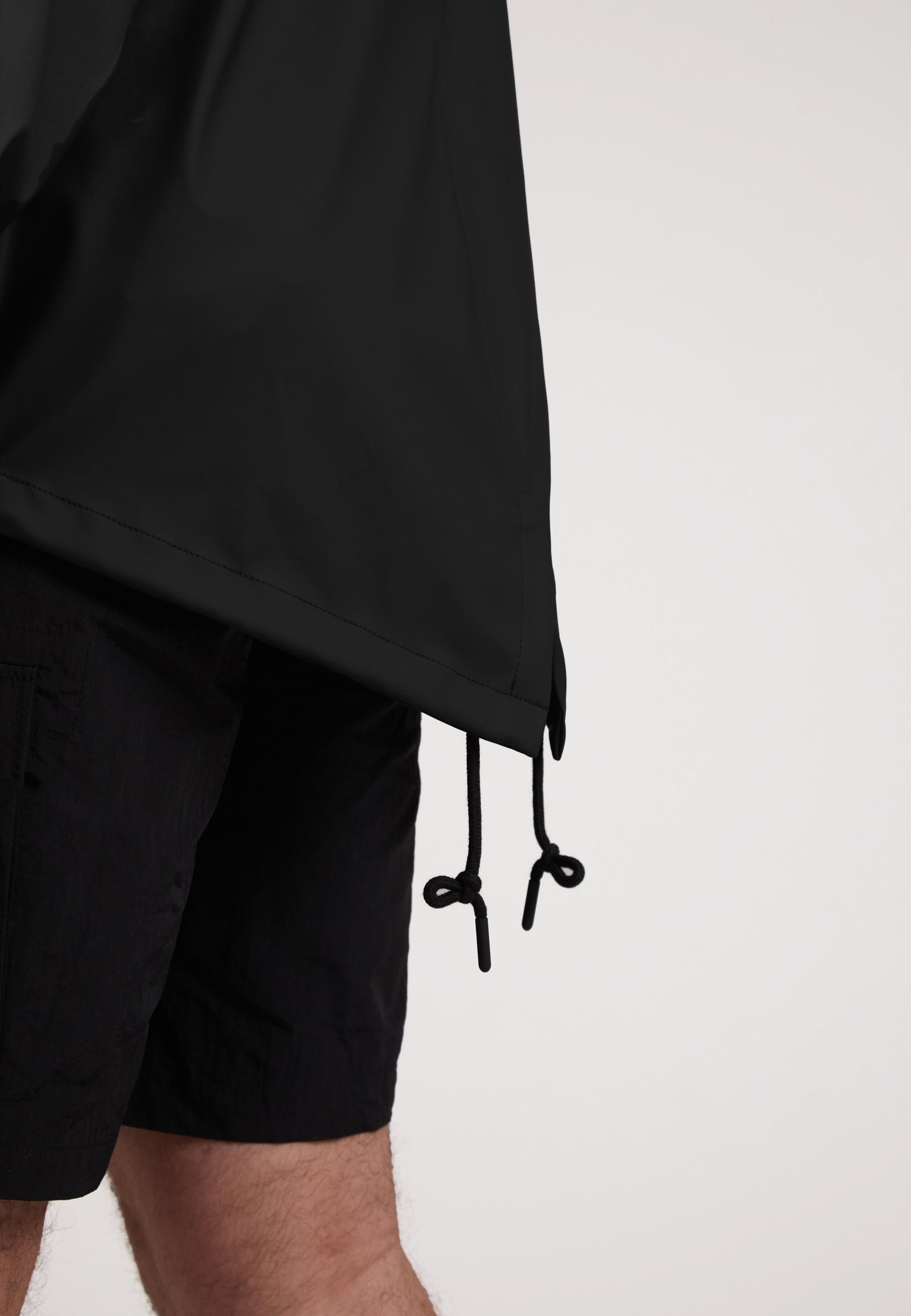 Close-up of ELEMENTS Unisex Raincoat 2.0 Black showcasing adjustable hem with drawstrings.