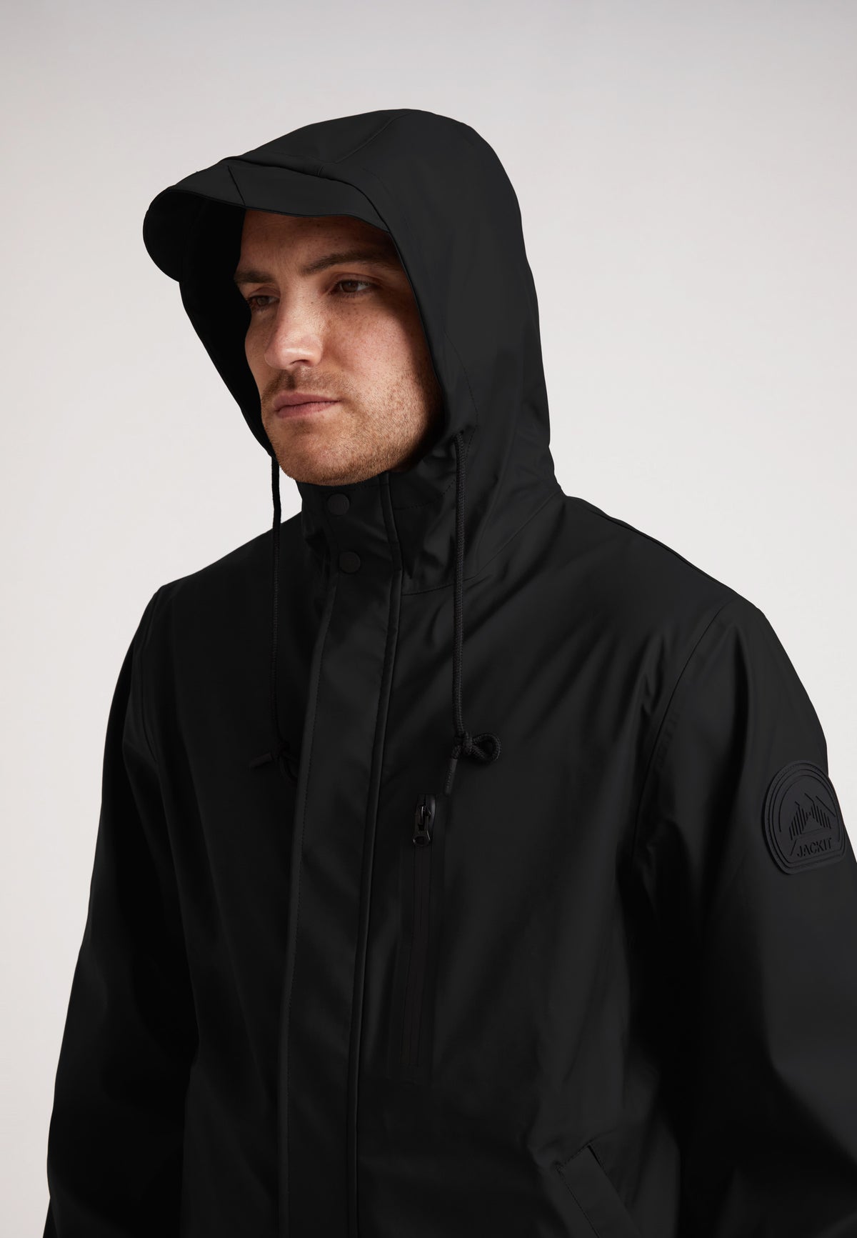 ELEMENTS Unisex Raincoat 2.0 Black worn by a man with a hood, showcasing its lightweight weather protection.