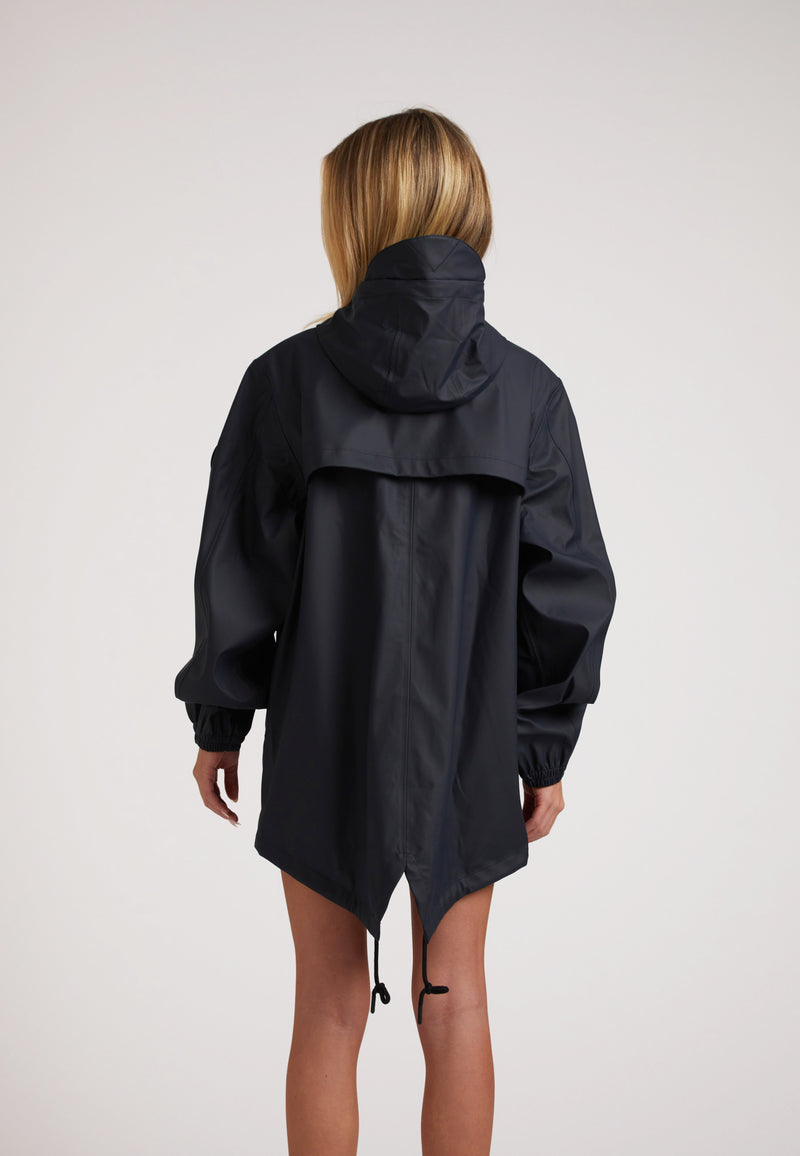 Back view of a woman wearing the ELEMENTS Raincoat 2.0 Navy, showcasing its hood and stylish design.