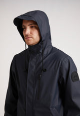 Man wearing ELEMENTS Unisex Raincoat 2.0 Navy with hood up, showcasing lightweight weather protection.