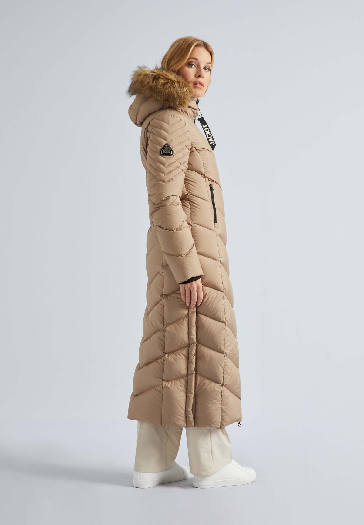 Extra long puffer coat womens, featuring a lightweight design with a hood and fur trim, shown in a stylish beige color.