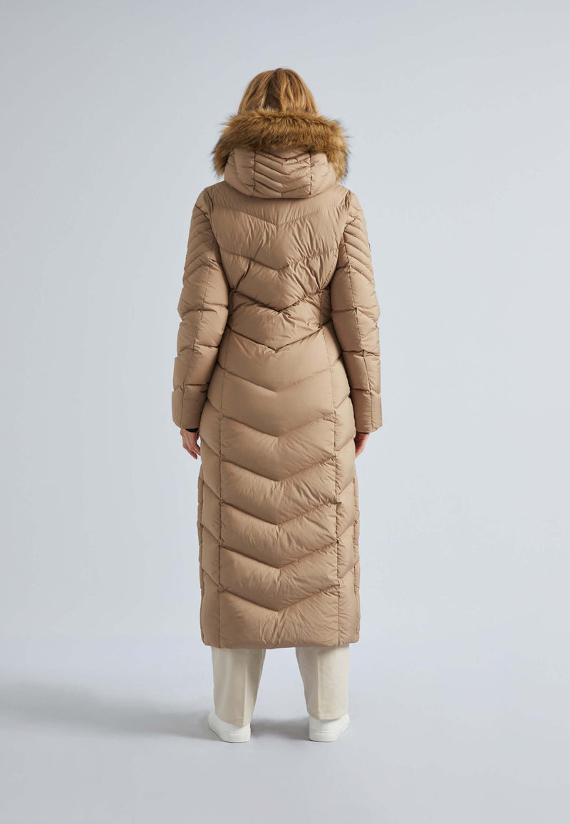 Back view of a woman in a beige extra long puffer coat womens with a hood and fur trim.