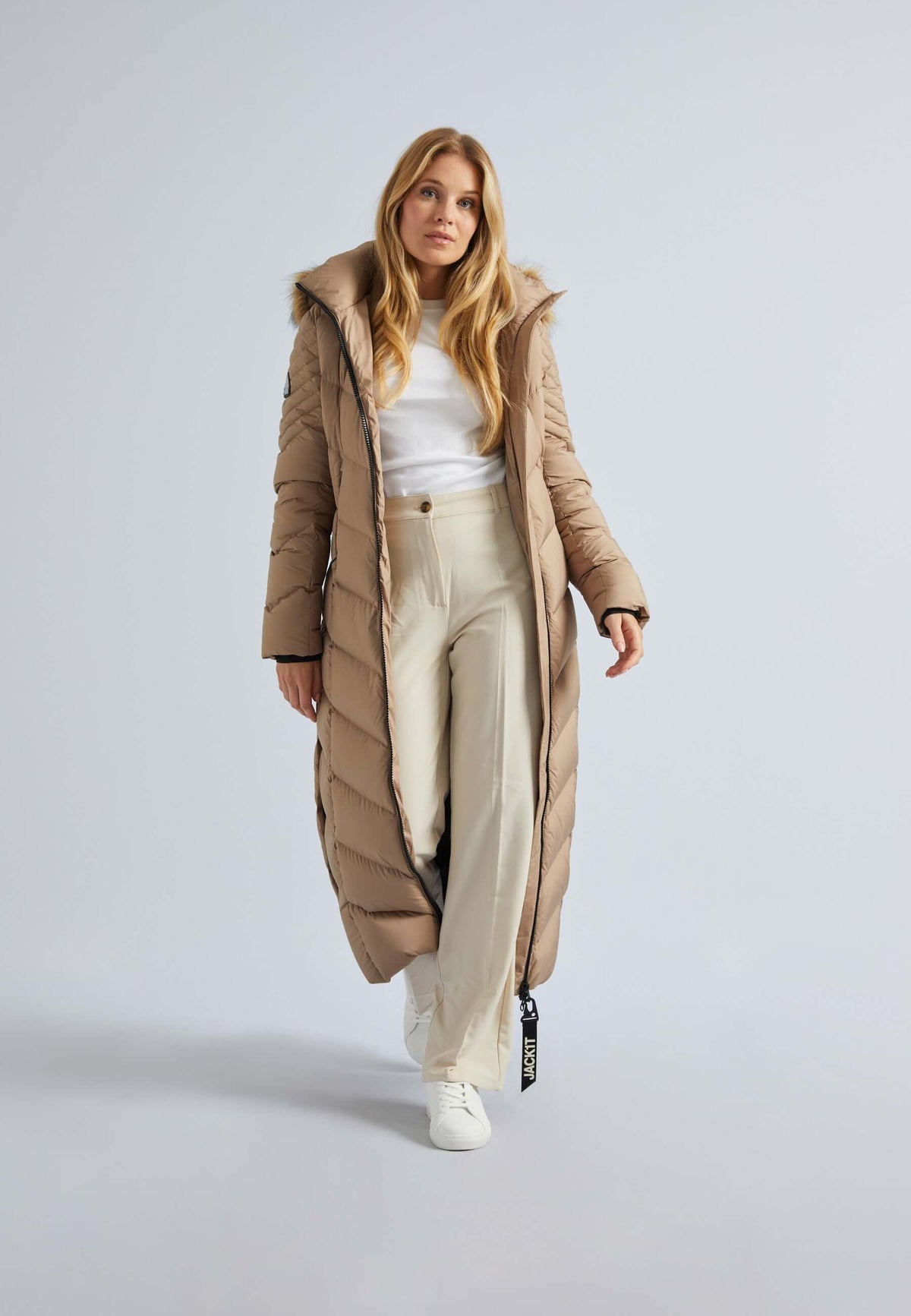 Woman wearing an extra long puffer coat womens with a stylish hood and comfortable fit, paired with wide-leg pants.