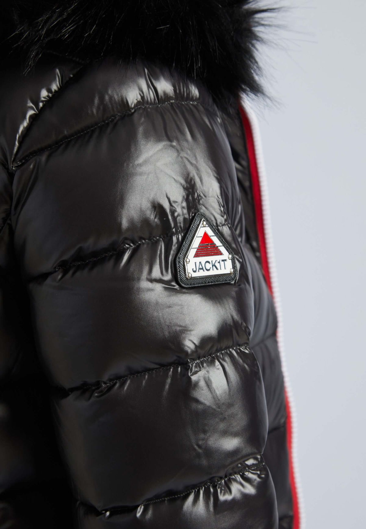 Close-up of black puffer jacket with fur hood, showcasing the shiny fabric and logo detail.