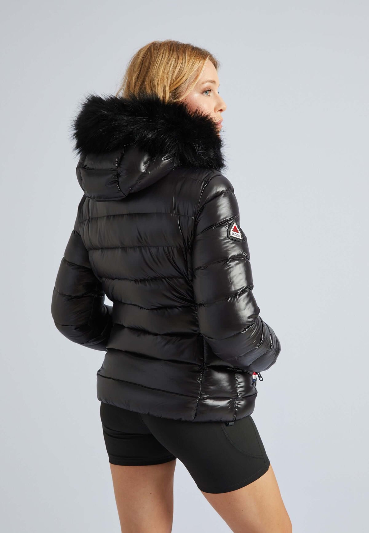 Woman wearing a black puffer jacket with fur hood, showcasing a stylish, lightweight down jacket design.