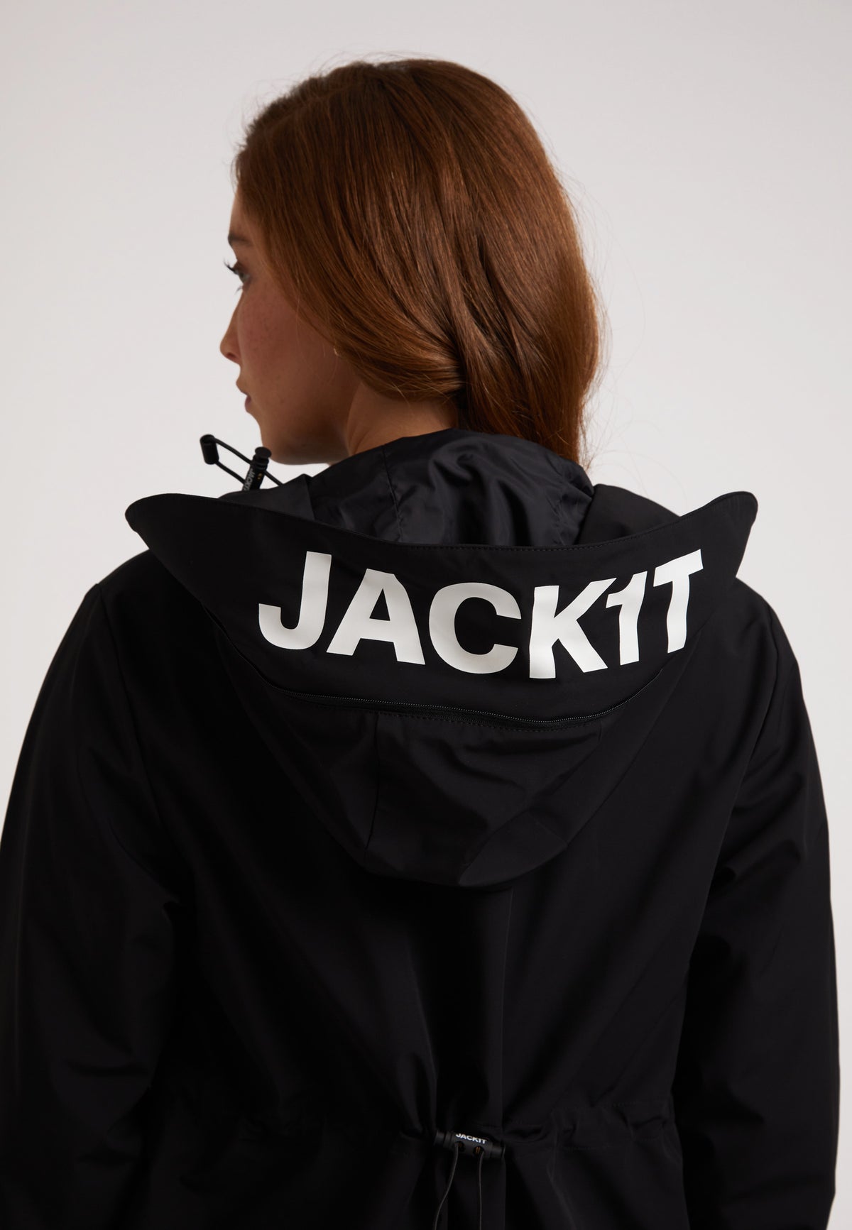 Back view of a woman wearing a black jacket with the word JACK1T on the hood.