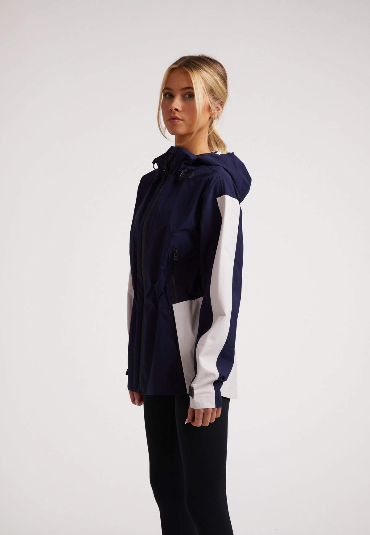 Model wearing the ISOTOPE ladies waterproof lightweight navy jacket with adjustable hood and cuffs.