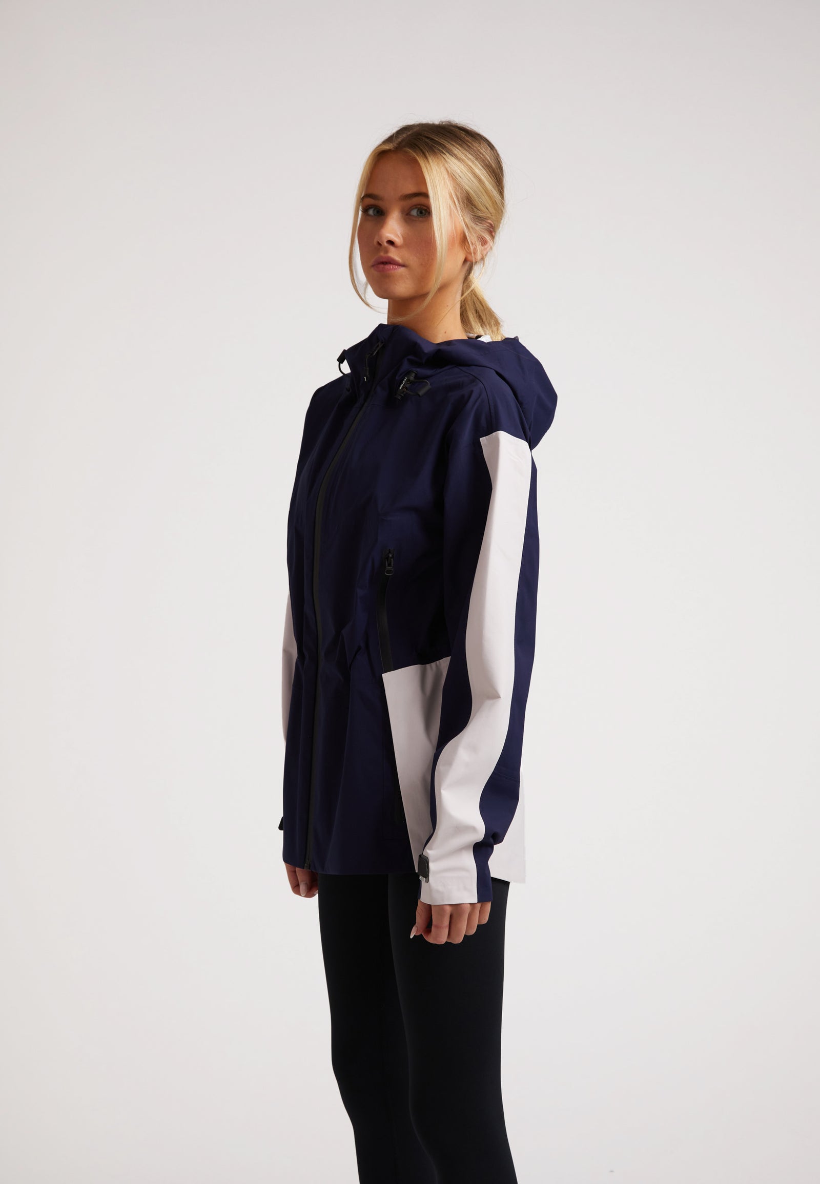 Model wearing the ISOTOPE ladies waterproof lightweight navy jacket with adjustable hood and cuffs.