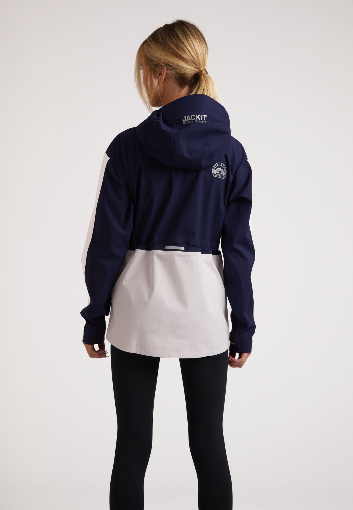 Back view of a woman wearing a ladies waterproof lightweight navy jacket with adjustable hood and stylish design.