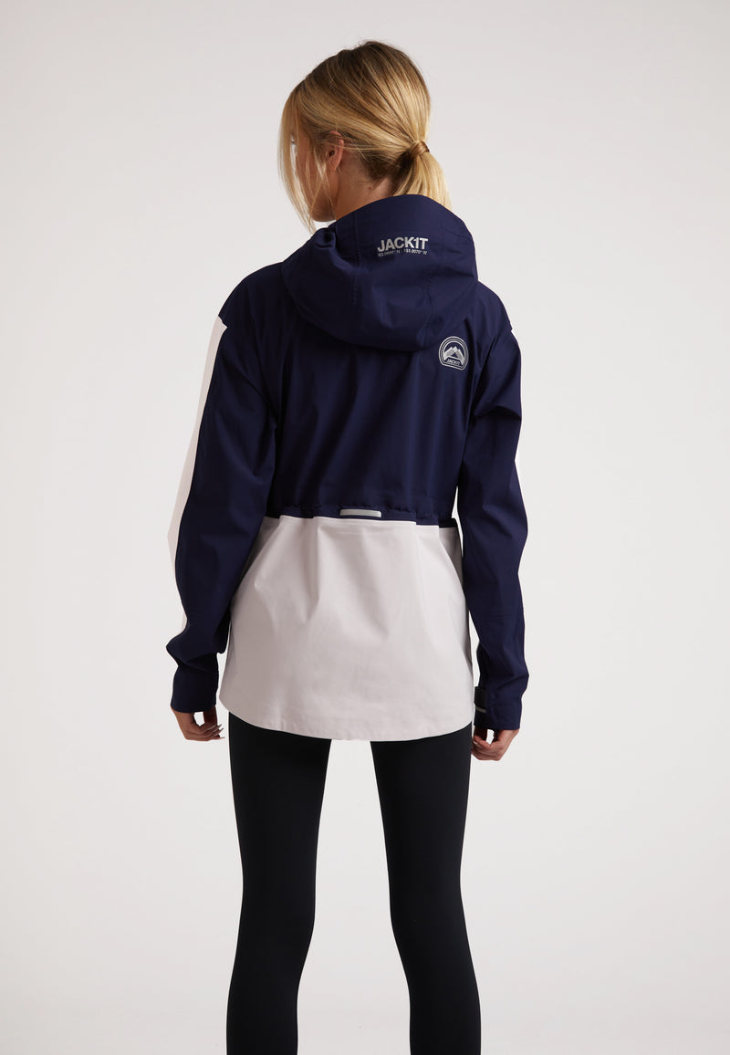Back view of a woman wearing a ladies waterproof lightweight navy jacket with adjustable hood and stylish design.