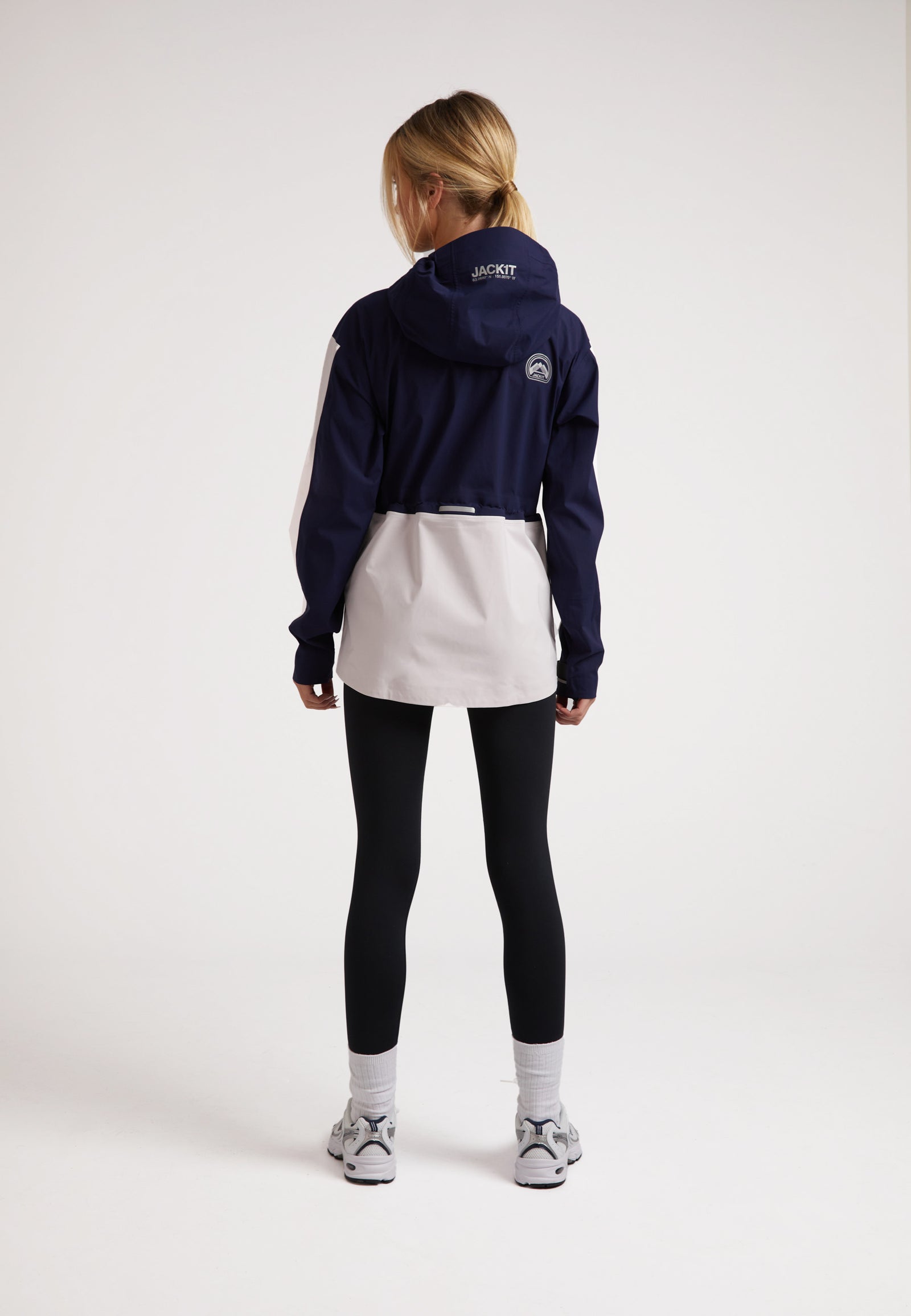 Model wearing a ladies waterproof lightweight navy jacket with adjustable hood and taped seams.