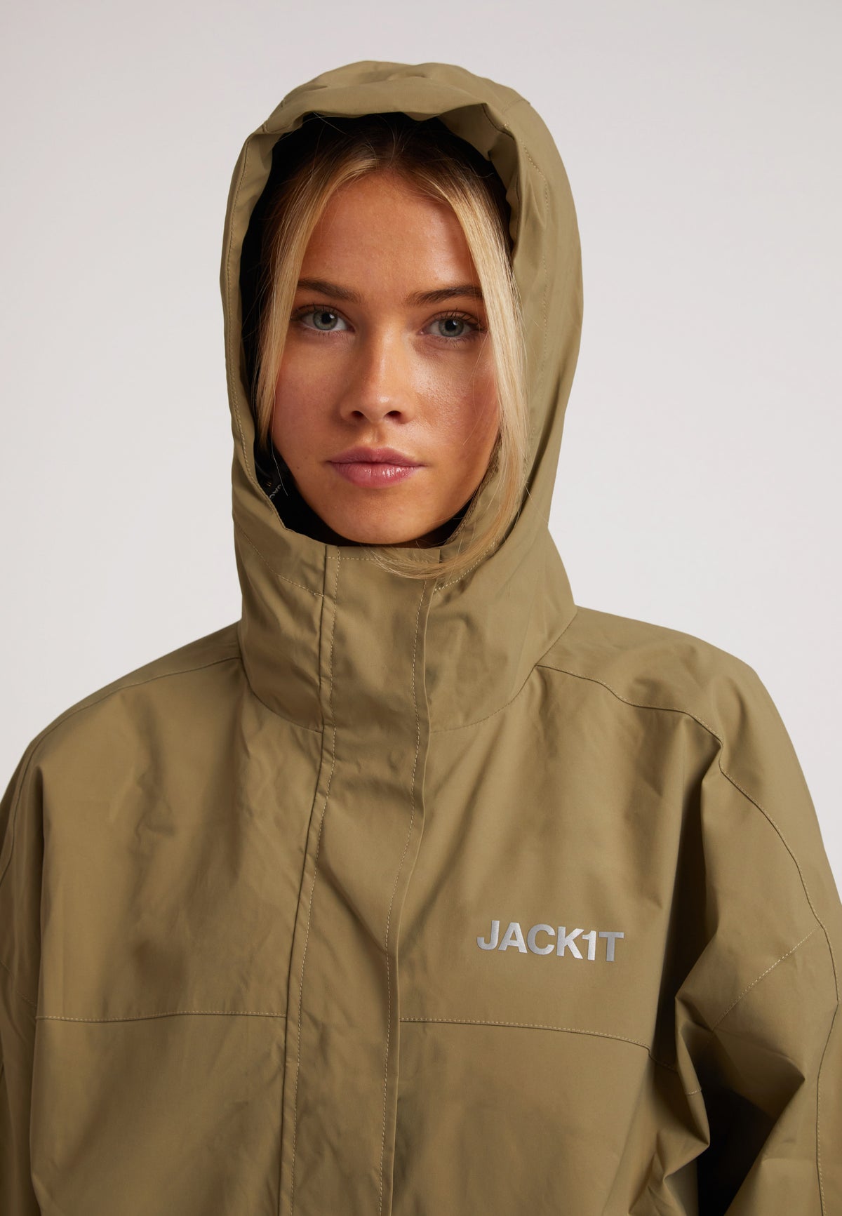 Ladies lightweight olive windbreaker on model wearing hood with a neutral background.
