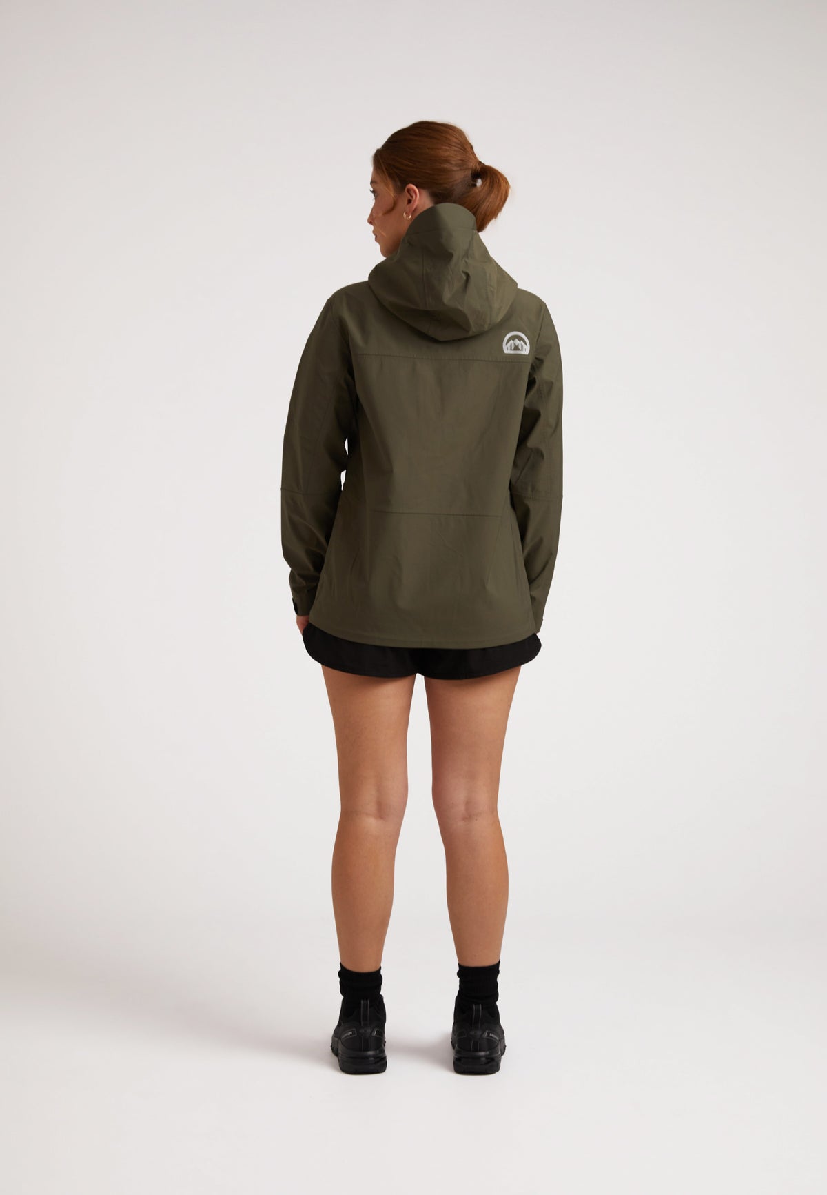 Waterproof ladies jacket in olive worn by a woman, showcasing the back view and hood design.
