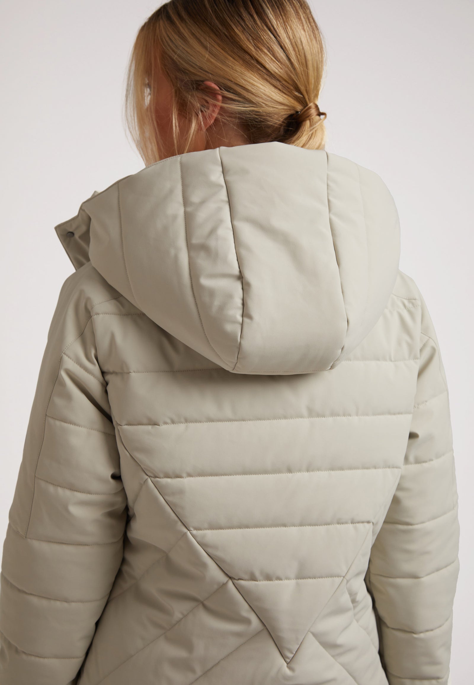 Back view of a model wearing the ISOTOPE Ladies padded lightweight stone jacket with an adjustable hood.