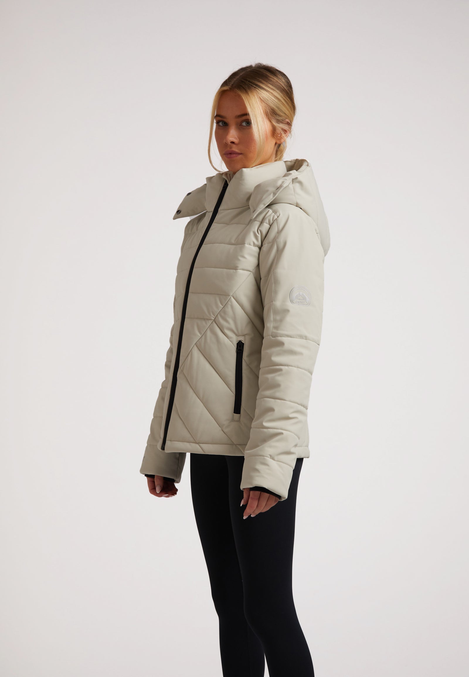 Ladies padded lightweight stone jacket displayed on a model, featuring a hood, side pockets, and stylish design.