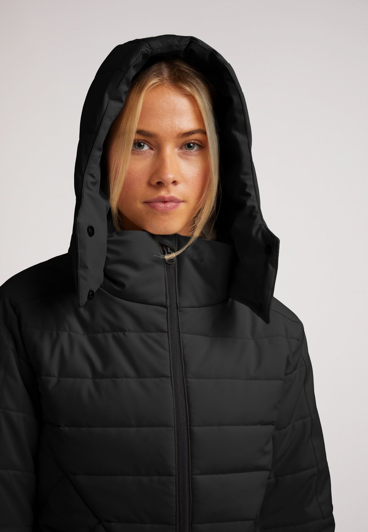 ISOTOPE Padded Jacket Black on a model, featuring an adjustable hood and windproof design for ultimate warmth.