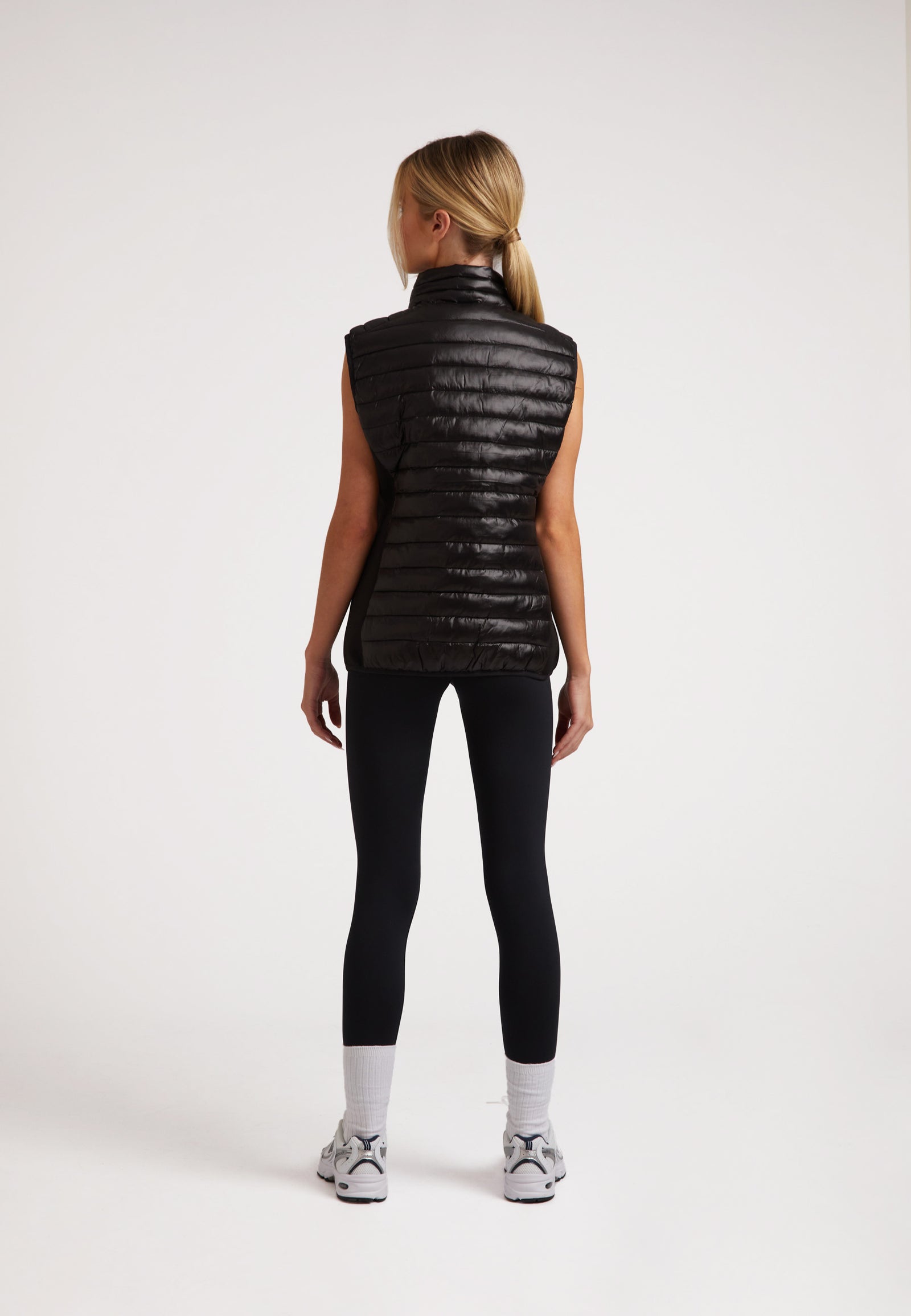 Back view of a model wearing the SPORTL1TE Funnel Lightweight Gilet 2.0 Lux Black, showcasing its sleek design and lightweight fabric.