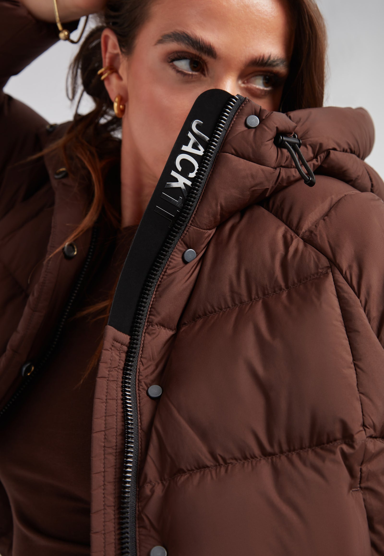 Ladies Cloud Crop Down Puffer Jacket in Mid Brown worn by a woman, showcasing its stylish design and oversized hood.