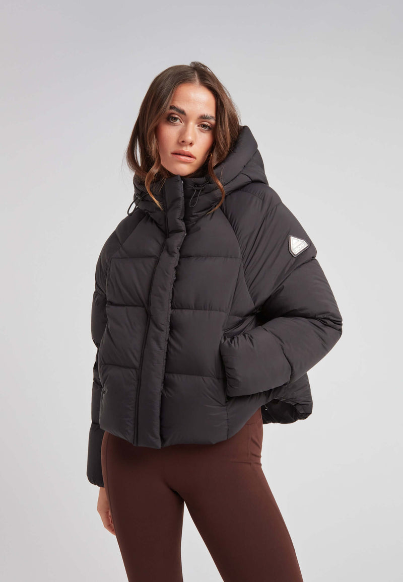 Short puffer jacket women in black with oversized hood and cropped cut, showcasing lightweight insulation.