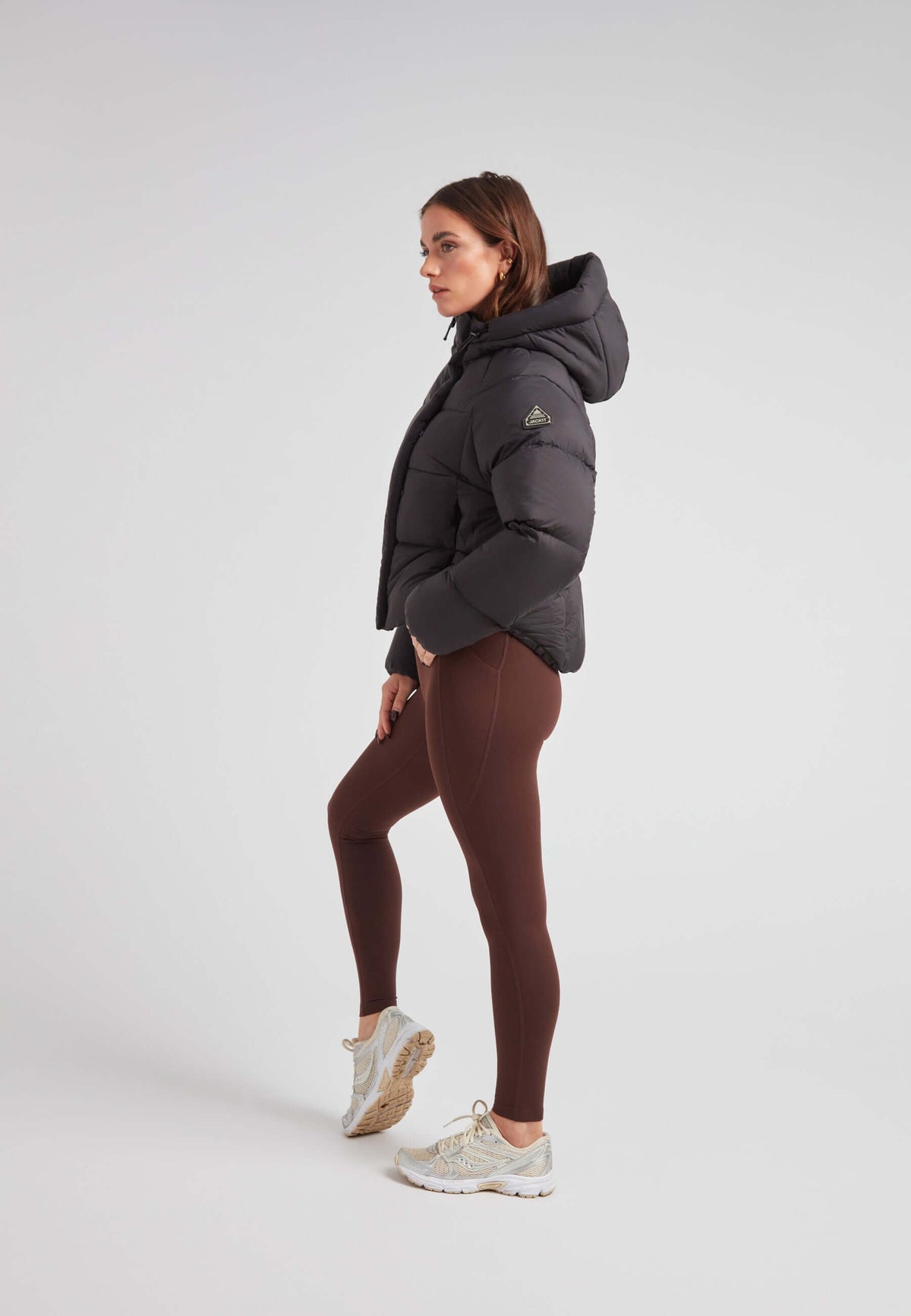 Short puffer jacket women worn by a model with leggings and sneakers, showcasing a sleek side profile.