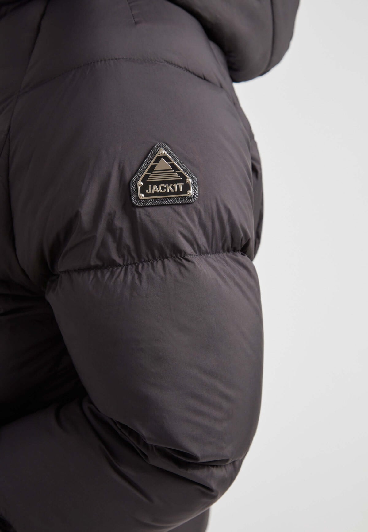 Close-up of JACK1T logo on the sleeve of a black short puffer jacket women, highlighting the stylish design and comfort features.