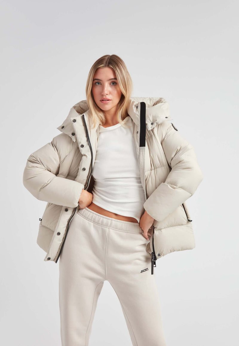 Cloud Prime Longline Down Puffer Jacket Stone worn by a model, showcasing its stylish mid-shine water-repellent design.
