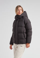 Model wearing the Cloud Prime Longline Down Puffer Jacket Black with adjustable hood in a studio setting.