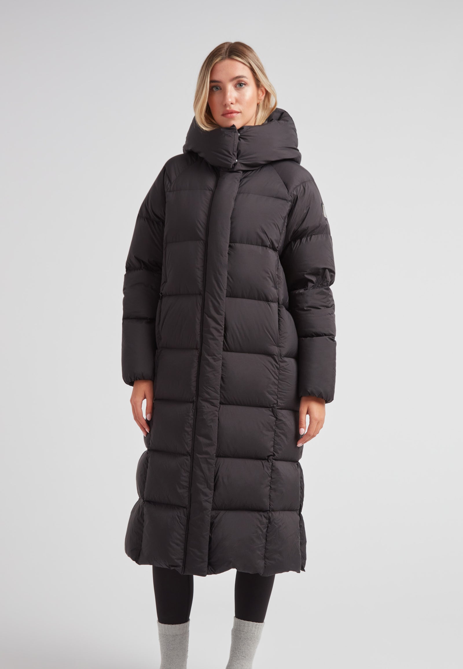 Model wearing a Long puffer jacket in black, featuring an adjustable hood and ankle-length design.
