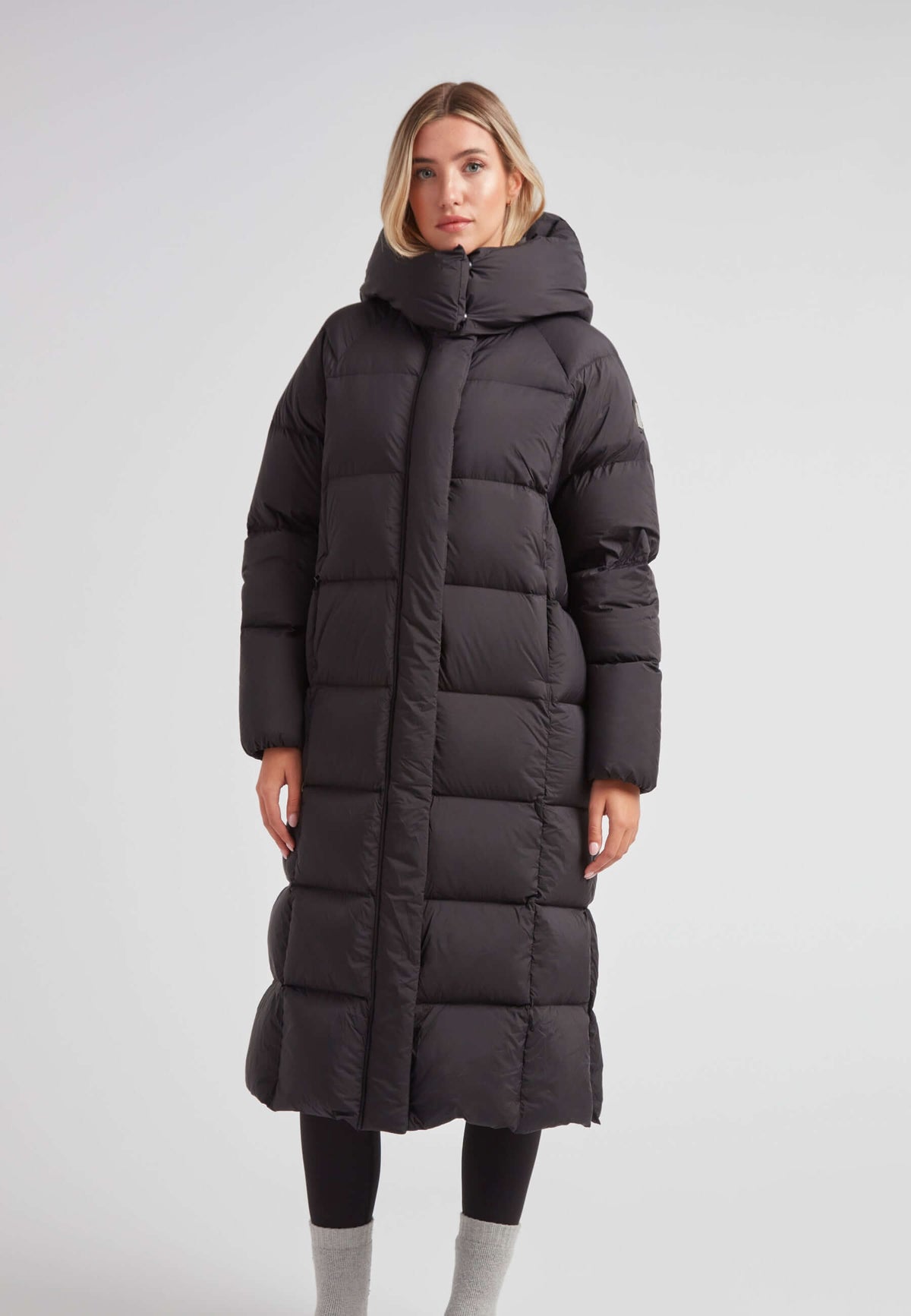 Model wearing a Long puffer jacket in black, featuring an adjustable hood and ankle-length design.