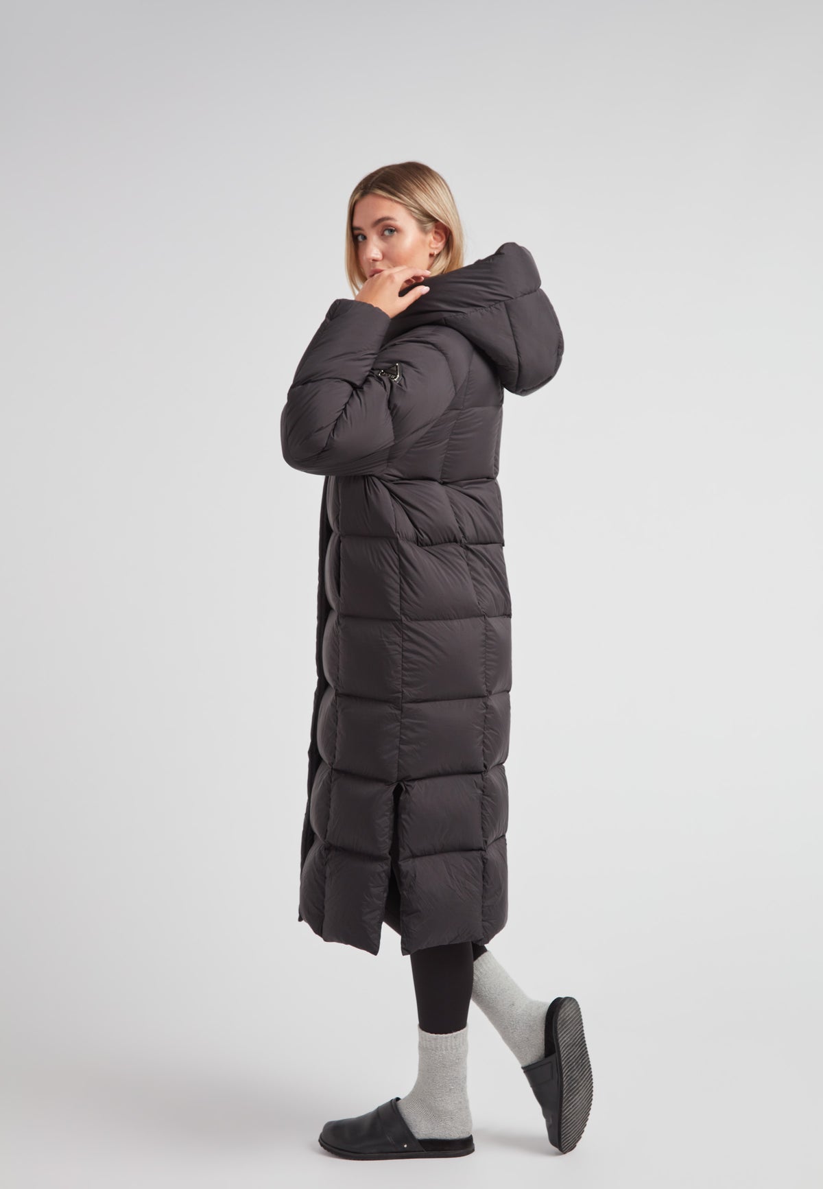 Model wearing a Long puffer jacket in black, showcasing its ankle-length and stylish design with an adjustable hood.