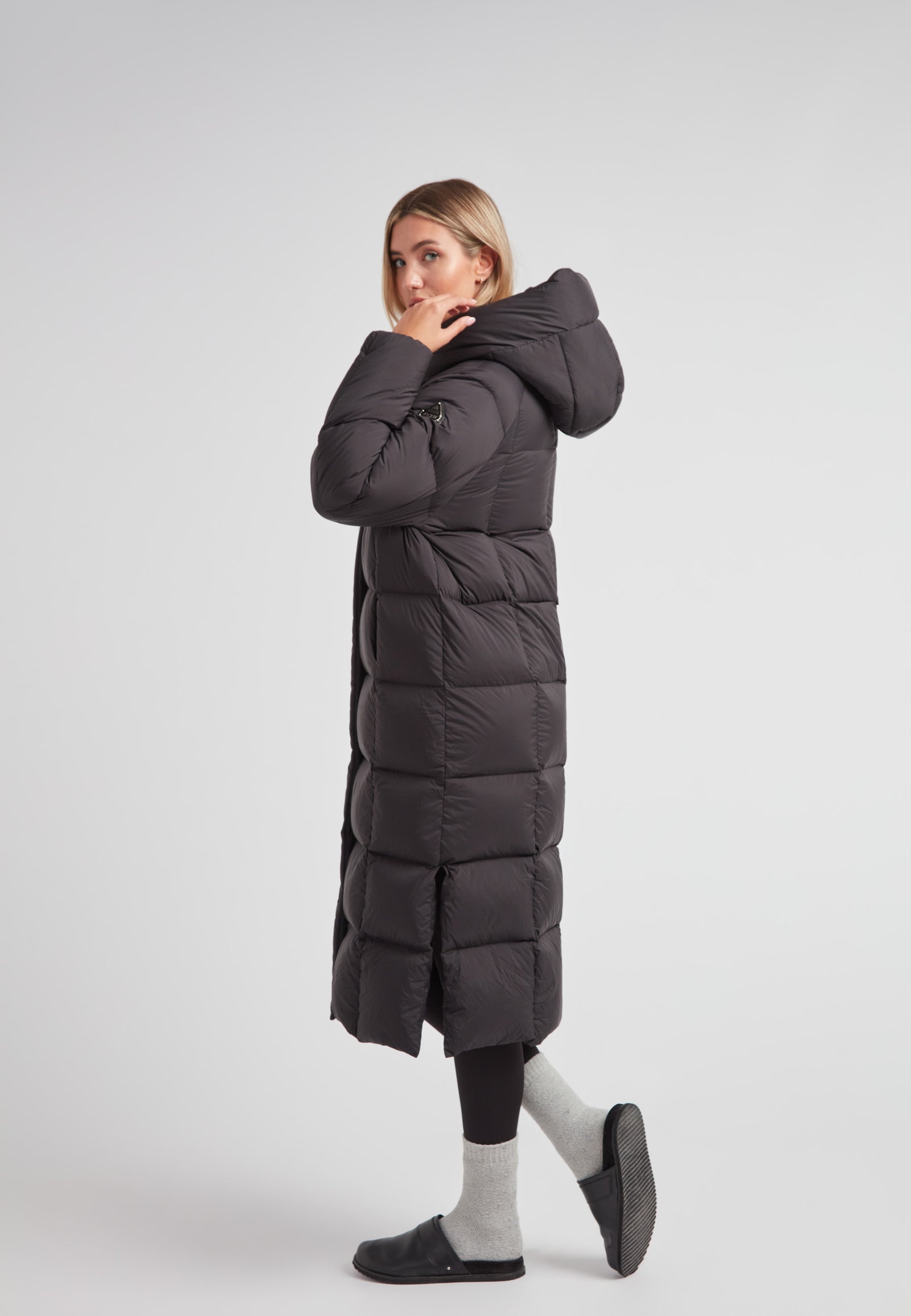 Model wearing a Long puffer jacket in black, showcasing its ankle-length and stylish design with an adjustable hood.
