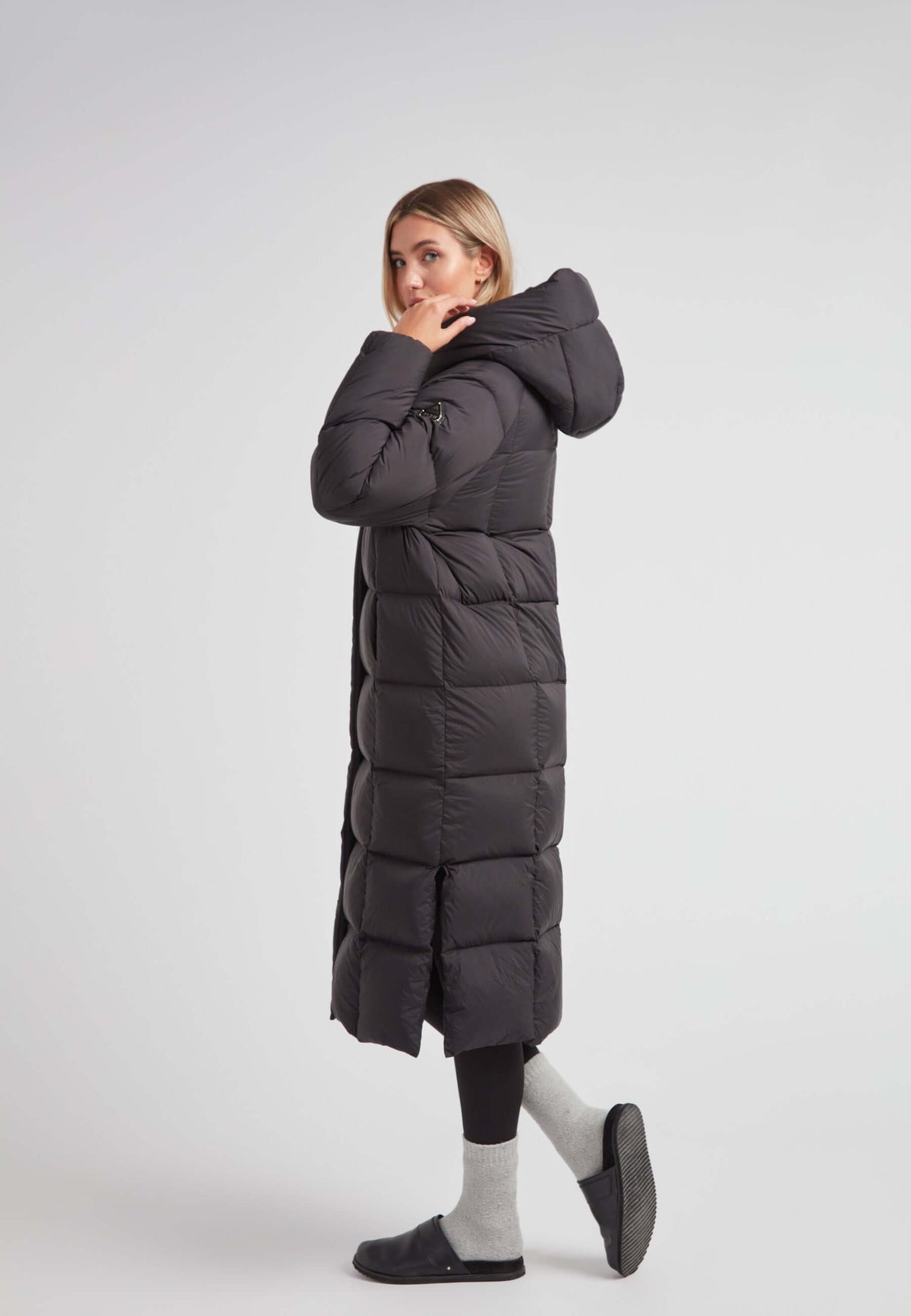 Model wearing a Long puffer jacket in black, showcasing its ankle-length and stylish design with an adjustable hood.