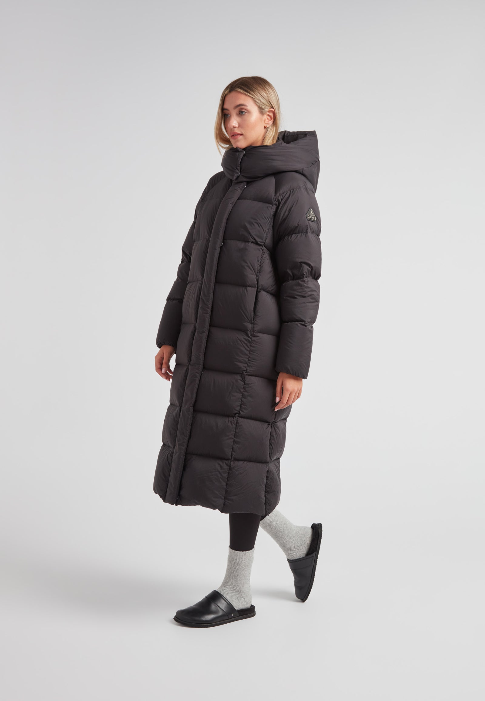 Woman wearing a stylish Cloud Ultra Long Down Puffer Coat, features include an adjustable hood and side slits, perfect for winter commutes.