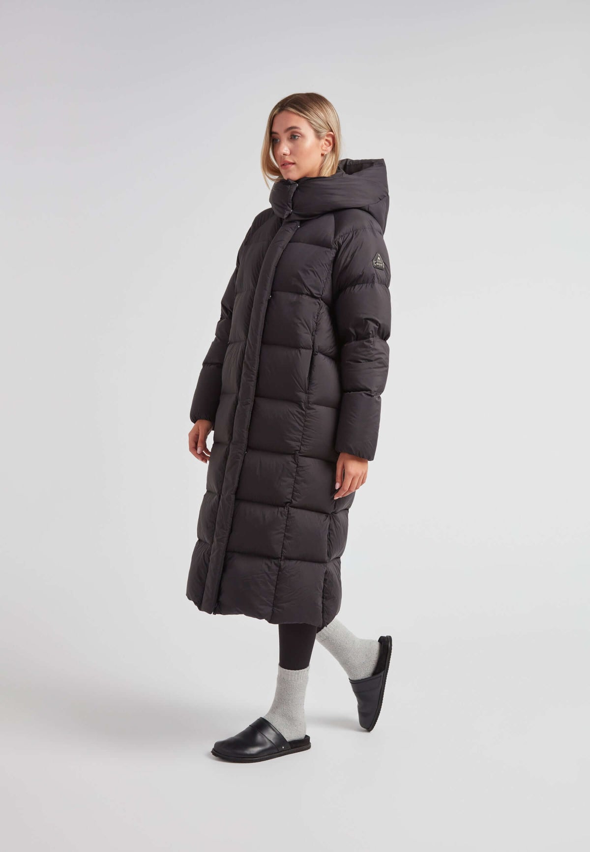 Woman wearing a stylish Cloud Ultra Long Down Puffer Coat, features include an adjustable hood and side slits, perfect for winter commutes.
