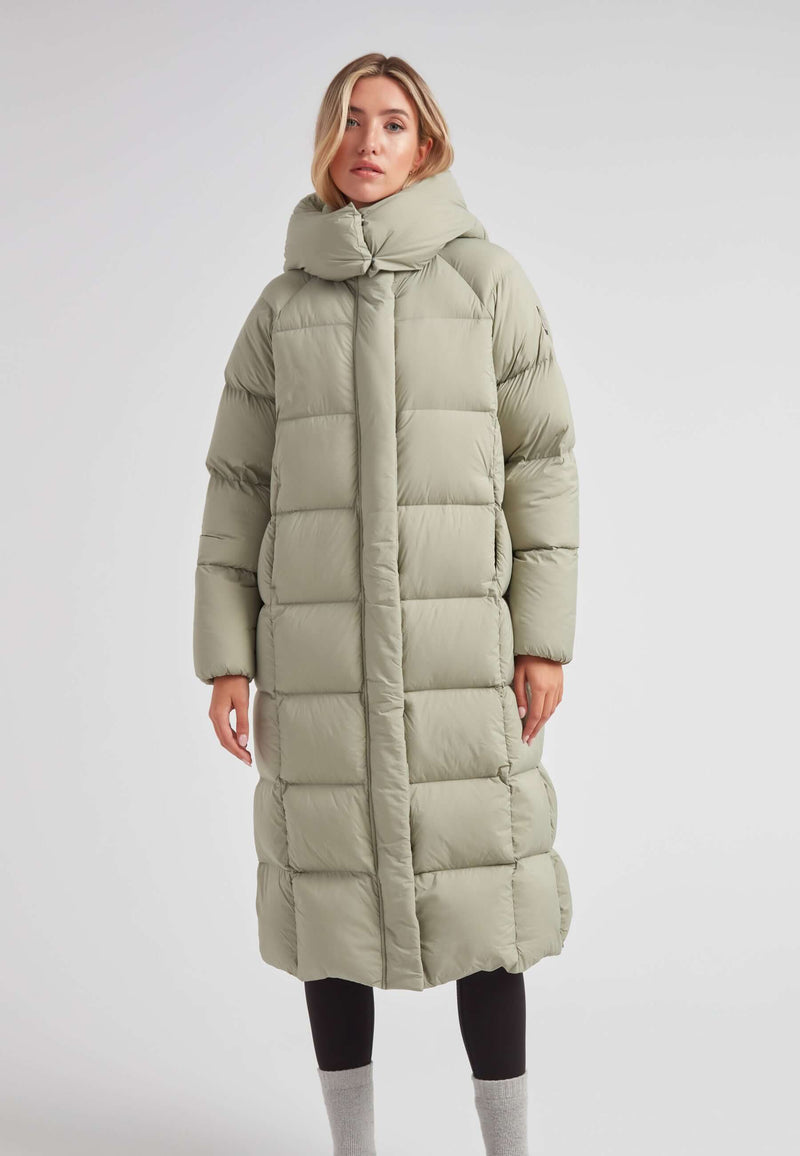 Woman wearing a Cloud Ultra Long Down Puffer Coat in a light green color, showcasing its stylish and warm design.