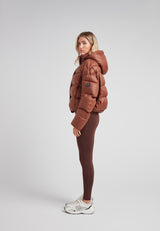 Cropped puffer in mocha brown with adjustable coverage worn by a model, showcasing street style and warmth.