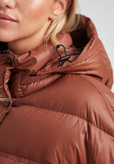 Close-up of a woman wearing a cropped puffer in mocha brown with adjustable coverage, showcasing the jacket's details.