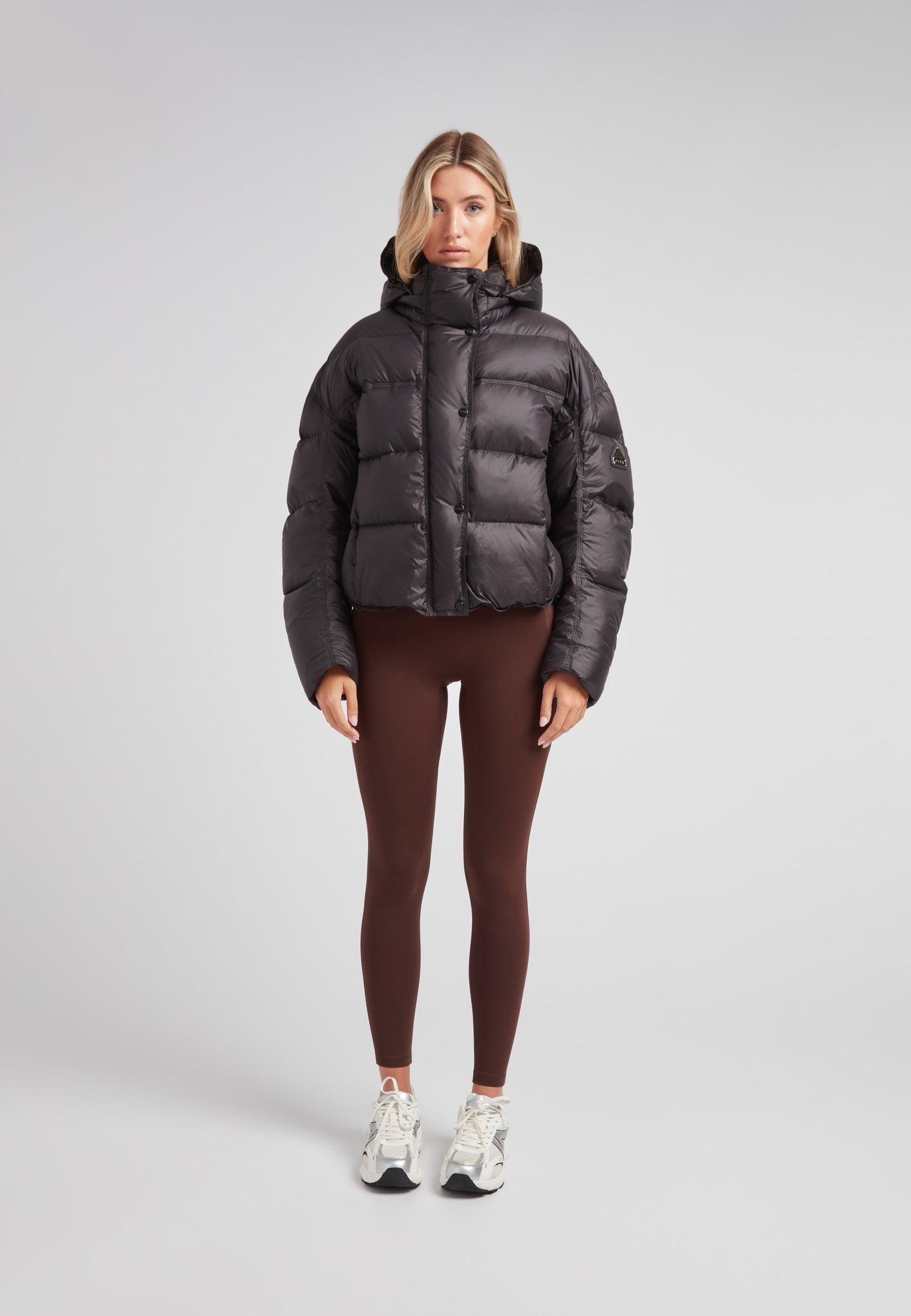 Cropped puffer in black with adjustable coverage, featuring oversized design and removable hood.