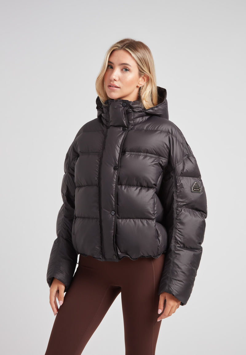 Cropped puffer in black with adjustable coverage worn by a model, showcasing oversized streetwear style.