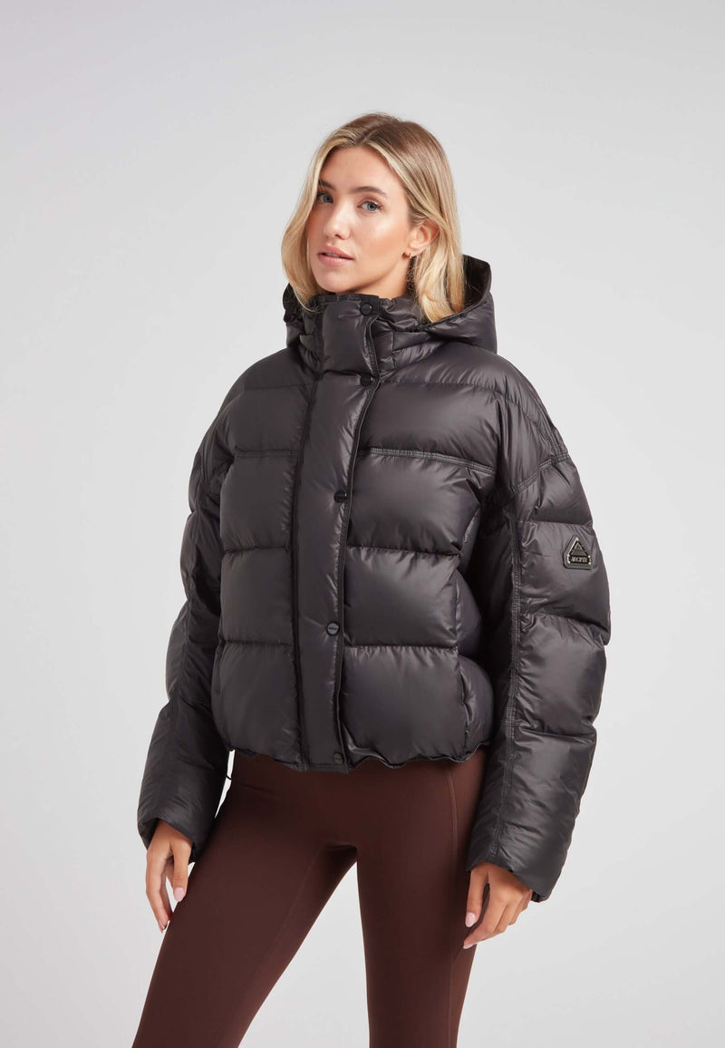 Cropped puffer in black with adjustable coverage worn by a model, showcasing oversized streetwear style.