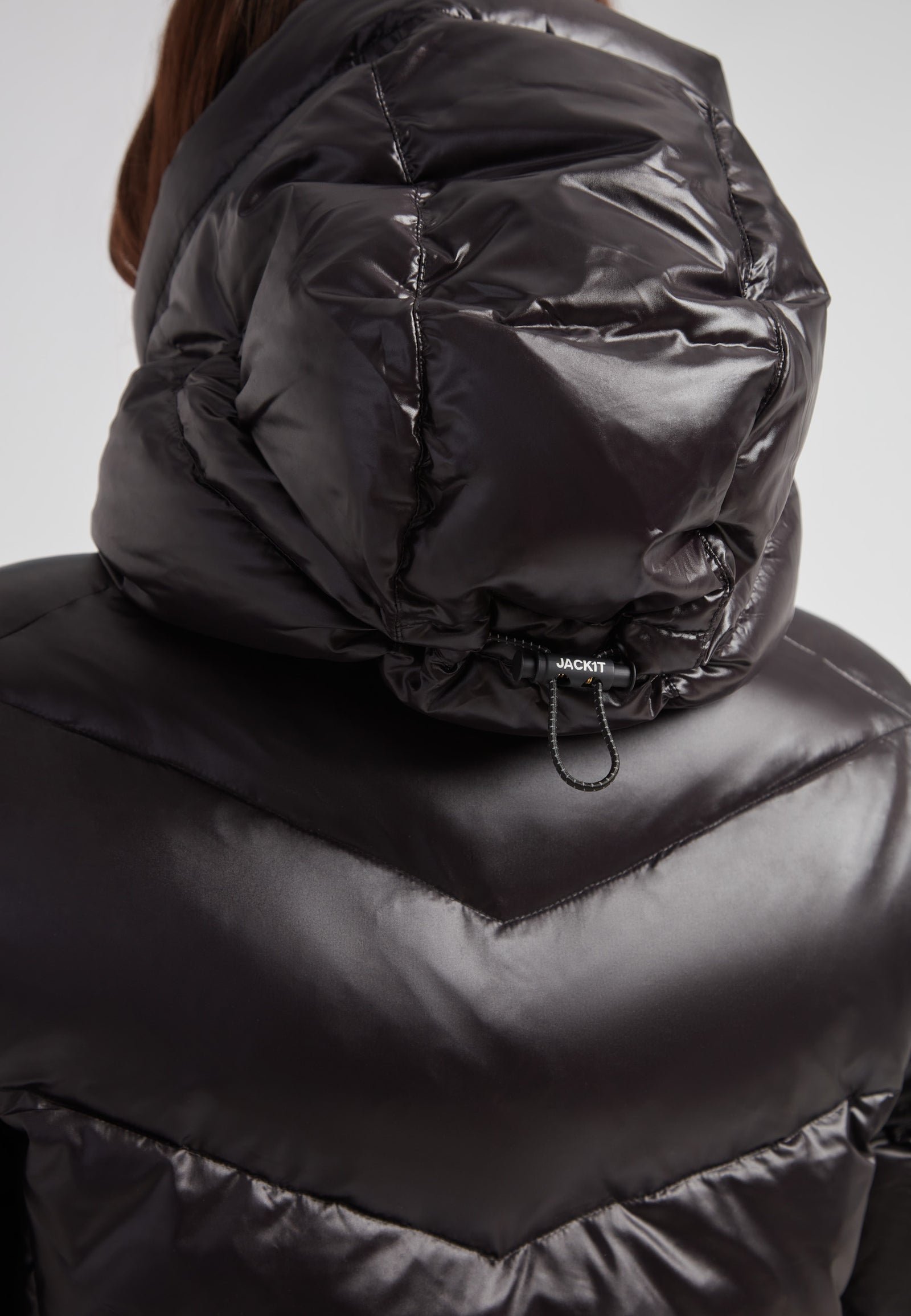 Close-up of the hood on the black thigh-length womens slick coat showcasing its sleek design and adjustable features.