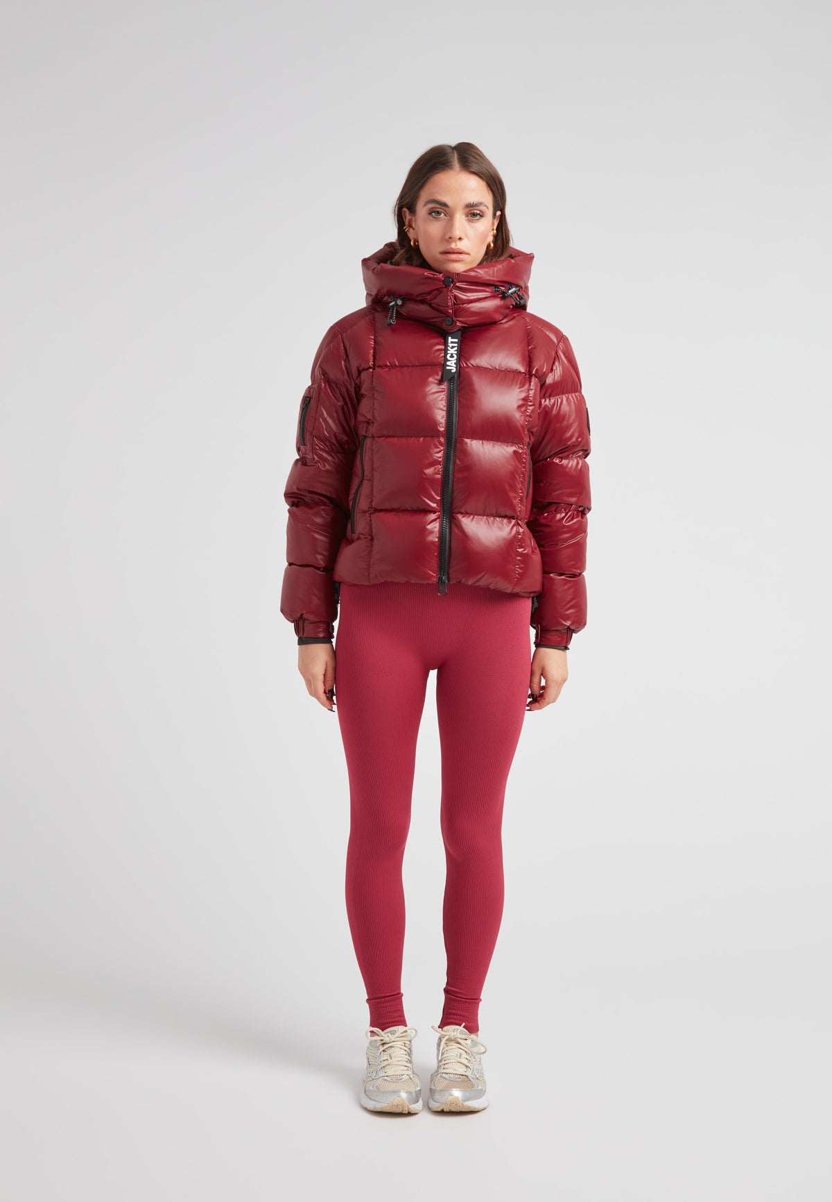 Woman wearing the EZ Boxed Crop Down Puffer Jacket Lux Cranberry with red leggings, ready for winter activities.