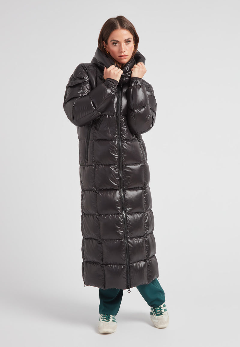 EZ Boxed Ultra Long Down Puffer Coat Lux Black worn by a woman, featuring a sleek design and bold length for winter warmth.