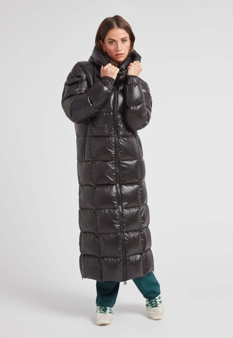 EZ Boxed Ultra Long Down Puffer Coat Lux Black worn by a woman, featuring a sleek design and bold length for winter warmth.