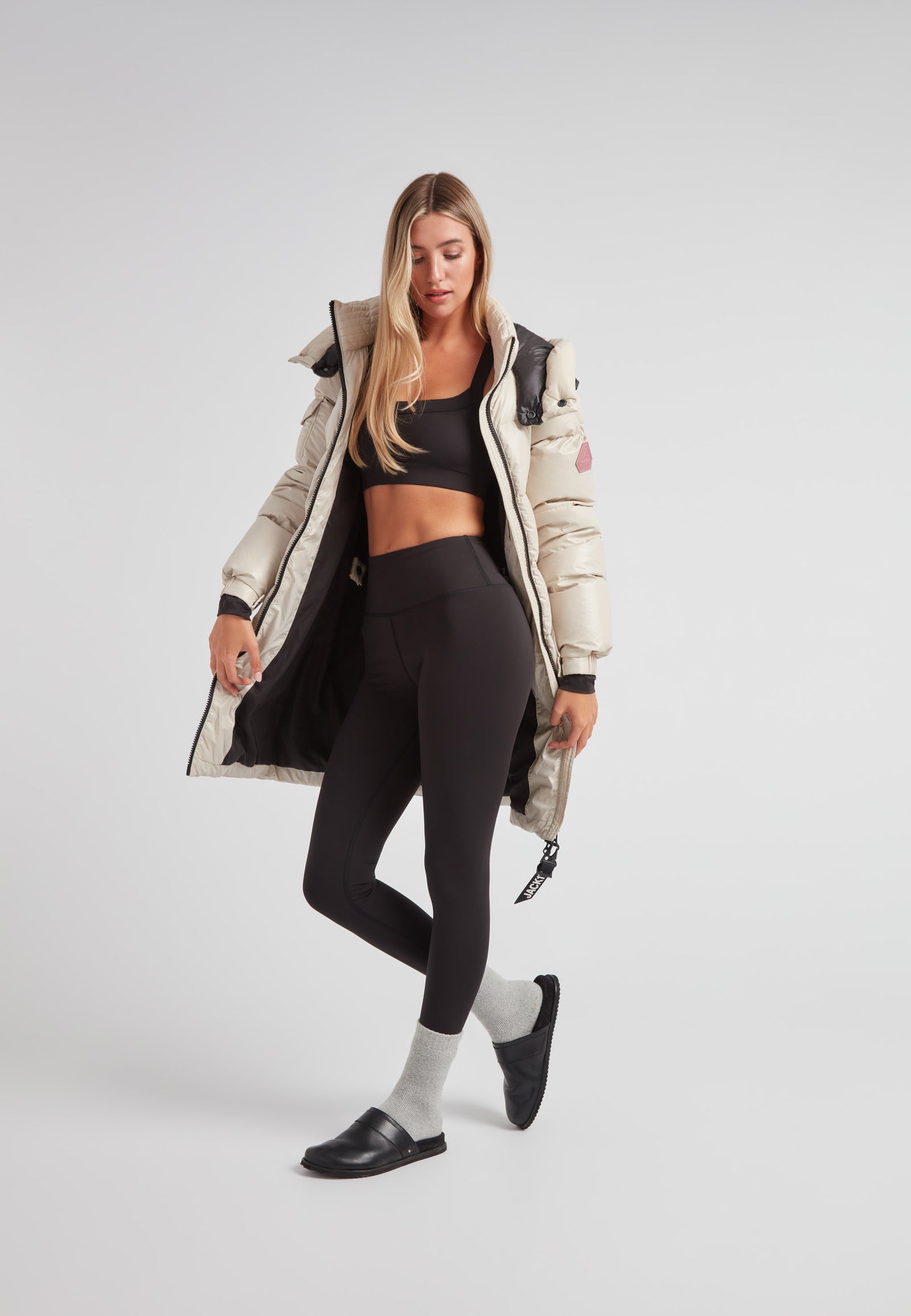 Woman wearing EZ Belted Down Puffer Coat Lux Stone with black leggings and socks, showcasing winter fashion style.